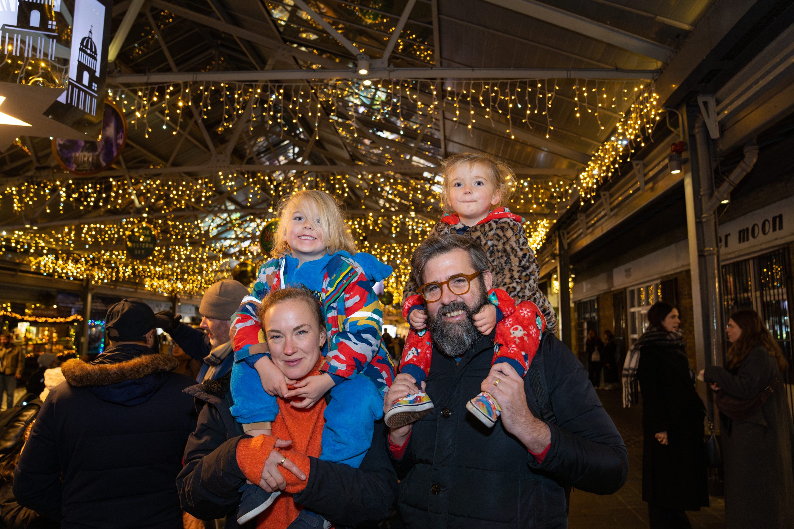 Greenwich Market Lantern Parade couple with children on their shoulders enjoy the lights